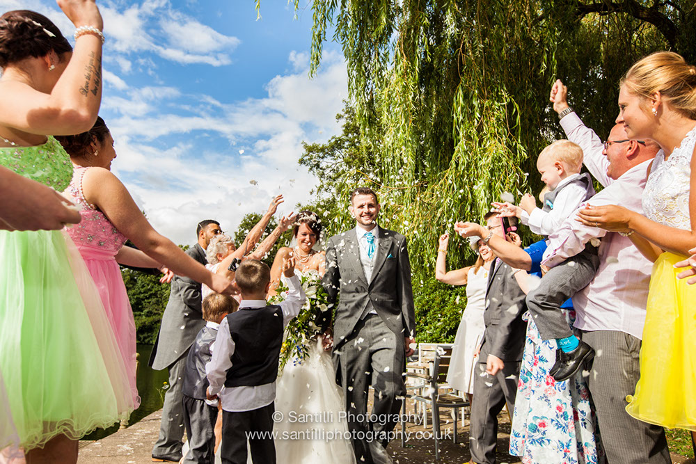 Throwing confetti over the bride and groom as they walk down the aisle of their family and friends