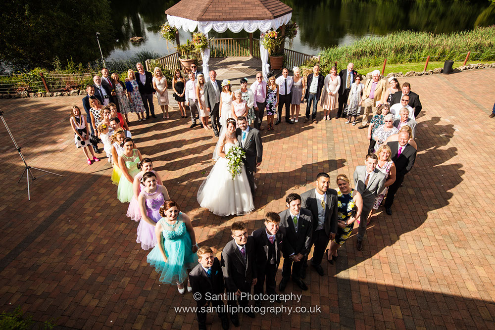 Family and friends surround the bride and groom in the shape of a heart representing a love and a happy future